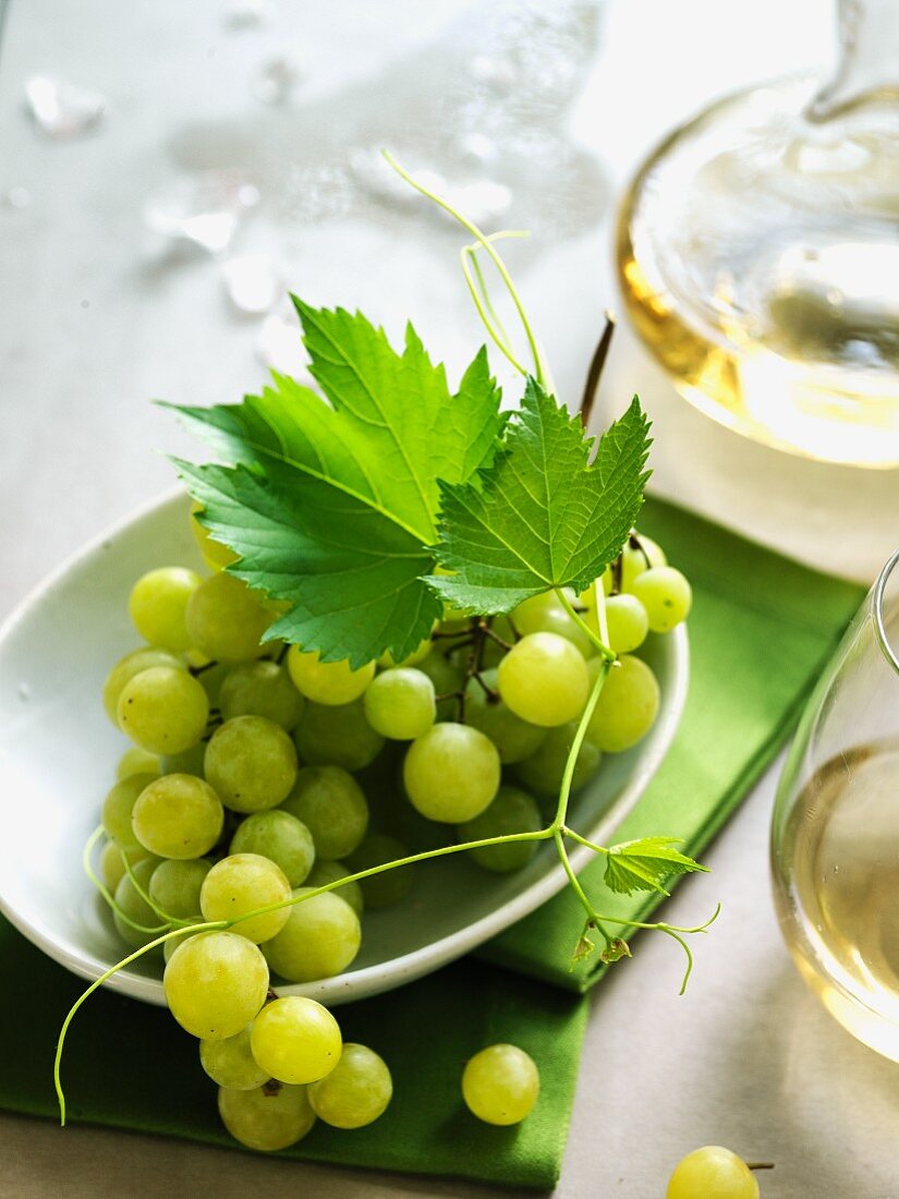 Green grapes with a glass of white wine and a carafe