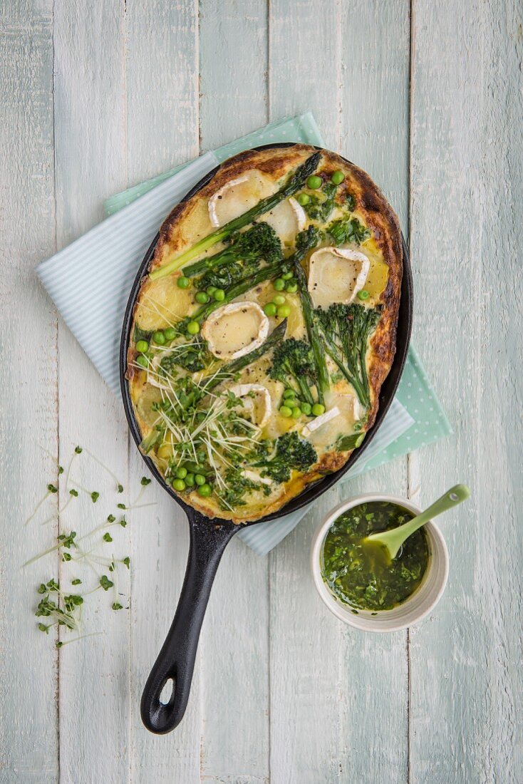 Potato and egg frittata with spring vegetables and gats cheese, basil oil on a side