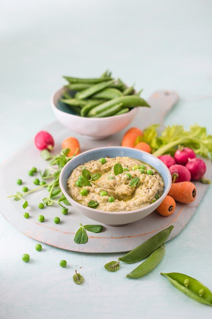 Houmous made of chickpeas, peas with mint and tahini, fresh vrgetables foe dipping on a side