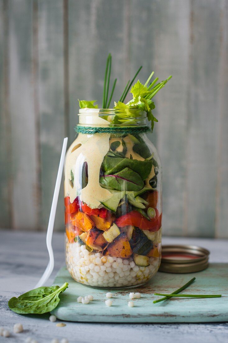 Salad jar for work lunch with giant cous cous, roasted vegetables, salad and yoghurt tahini and smoked paprika dressing