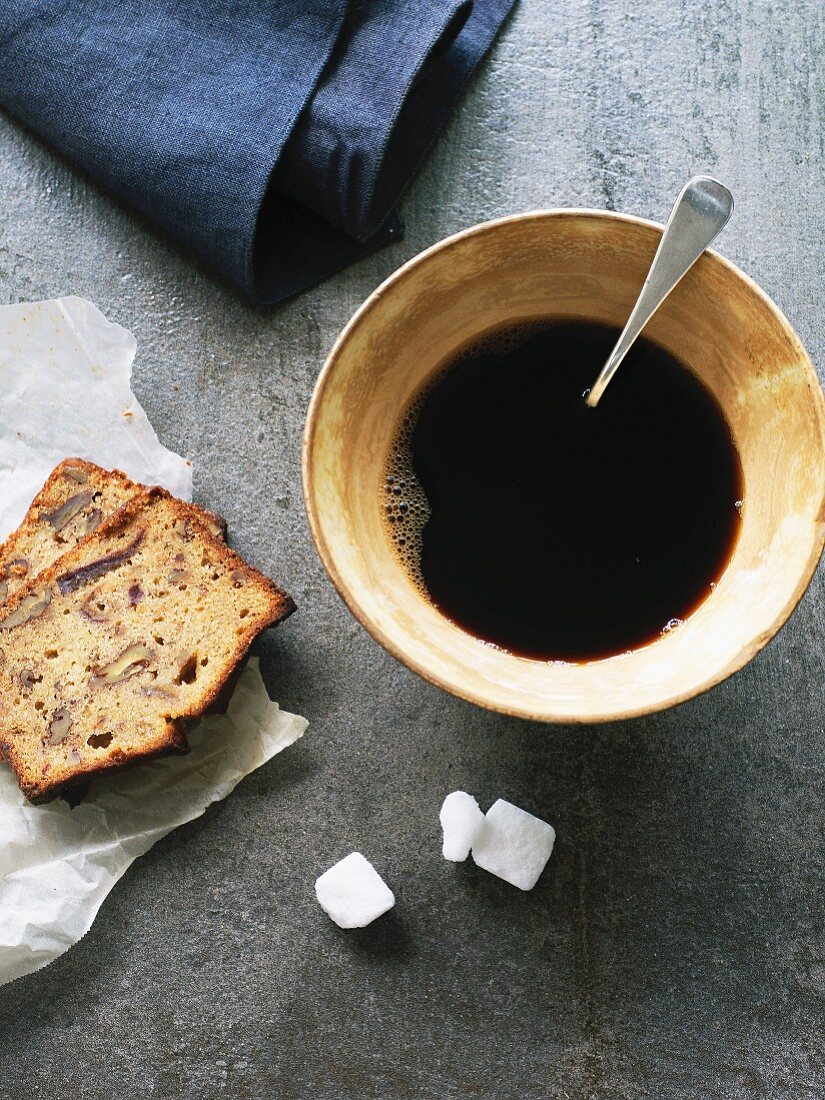 Schwarzer Kaffee in rustikaler Tasse und zwei Stücke Dattel-Pecannuss-Kuchen