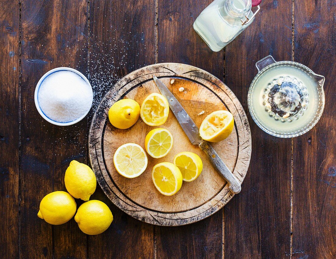 Frisch gepresste Zitronen mit Zucker und eine Flasche hausgemachte Limonade