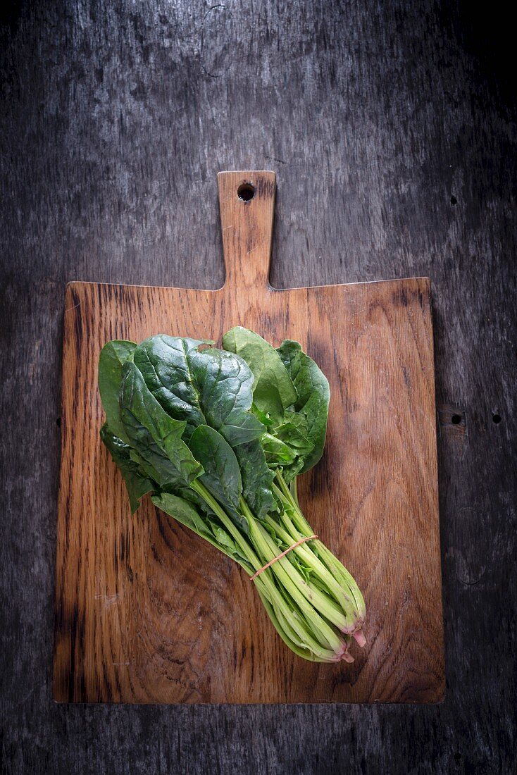 A bundle of spinach on a chopping board