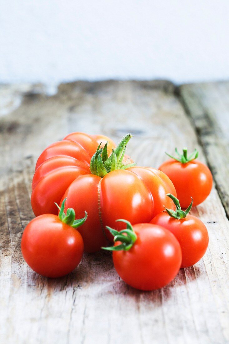 Various types of tomatoes on wooden background