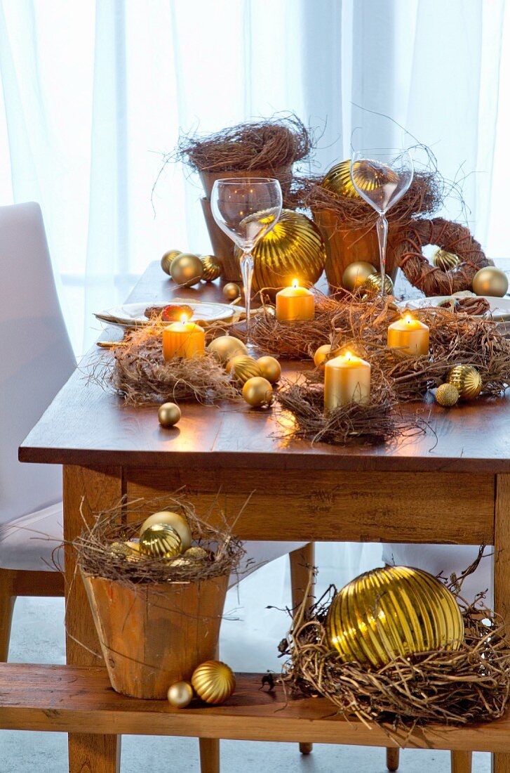 Wildkrautkränzchen mit goldenen Kugeln und Kerzen als weihnachtliche Tischdekoration
