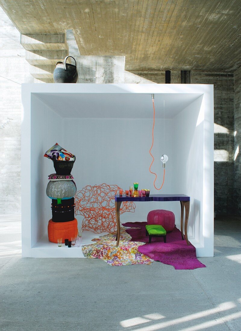 Stacked pouffes in white cube in front of concrete wall