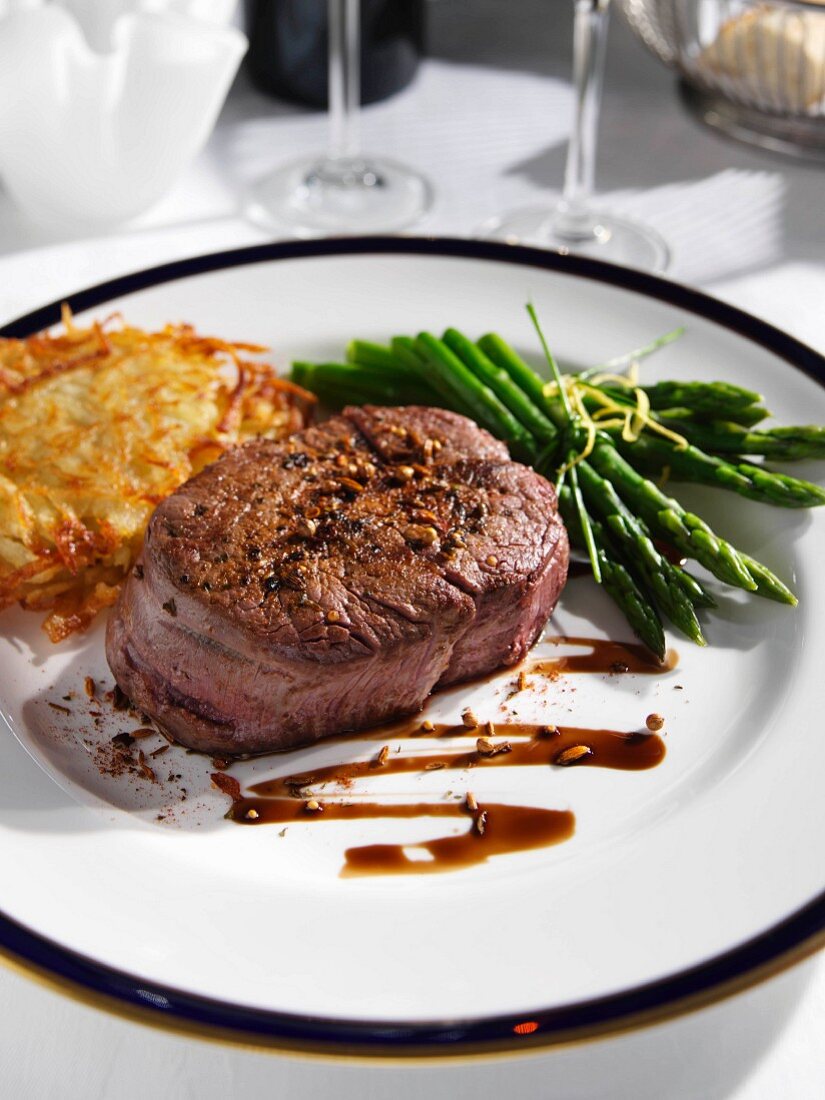 Rinderfiletsteak mit grünem Spargel und Rösti auf Teller