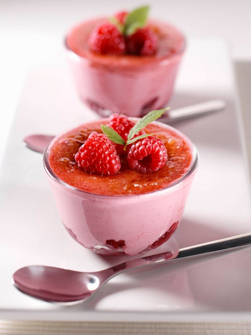 Raspberry creme brulee in two glasses decorated with raspberries