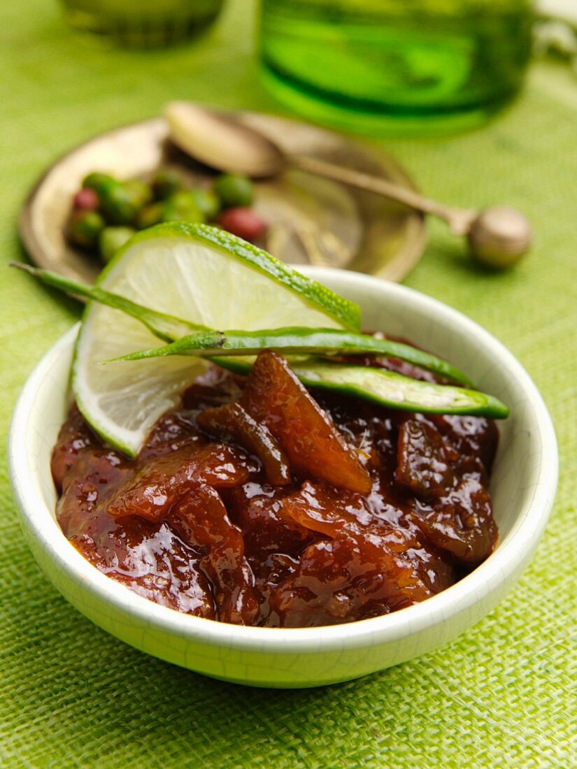 A bowl of lime and chilli chutney with a green background table setting