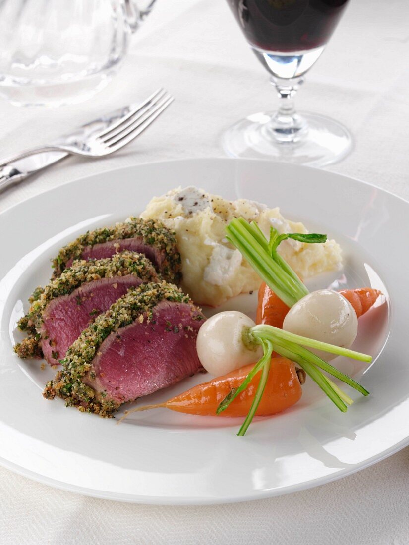 A plate of lamb loin in a herb crust with vegetables