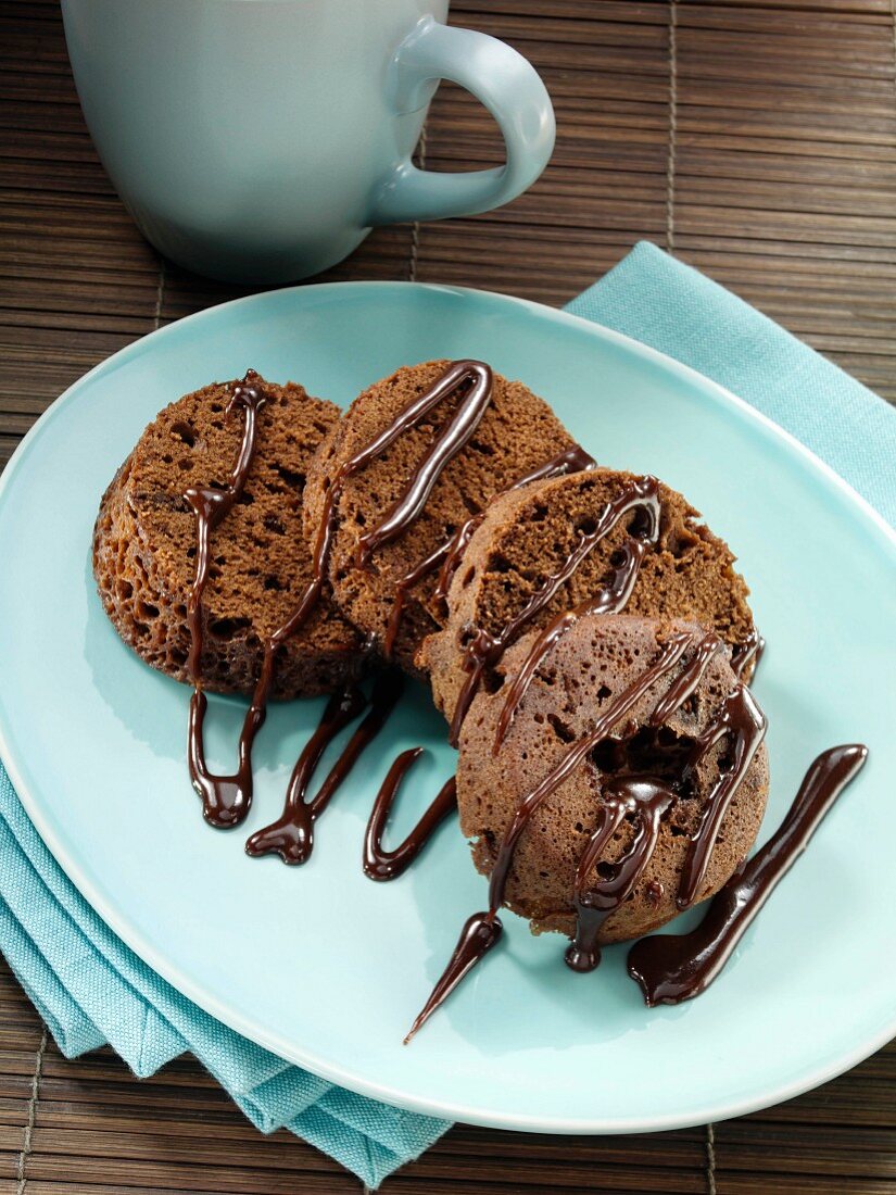Mokkakuchen mit Schokoladensauce in runden Scheiben auf Teller