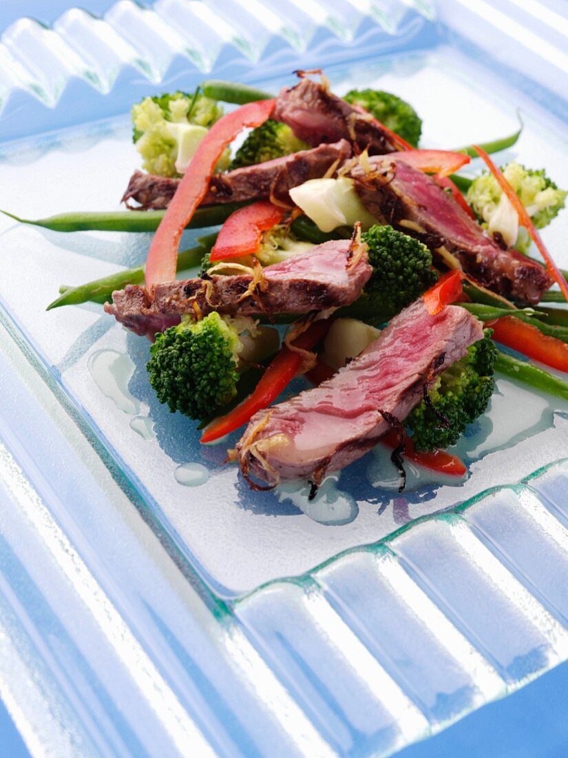 Gegrillte Rindersteakstreifen auf Gemüsesalat mit Brokkoli, Bohnen und Paprika