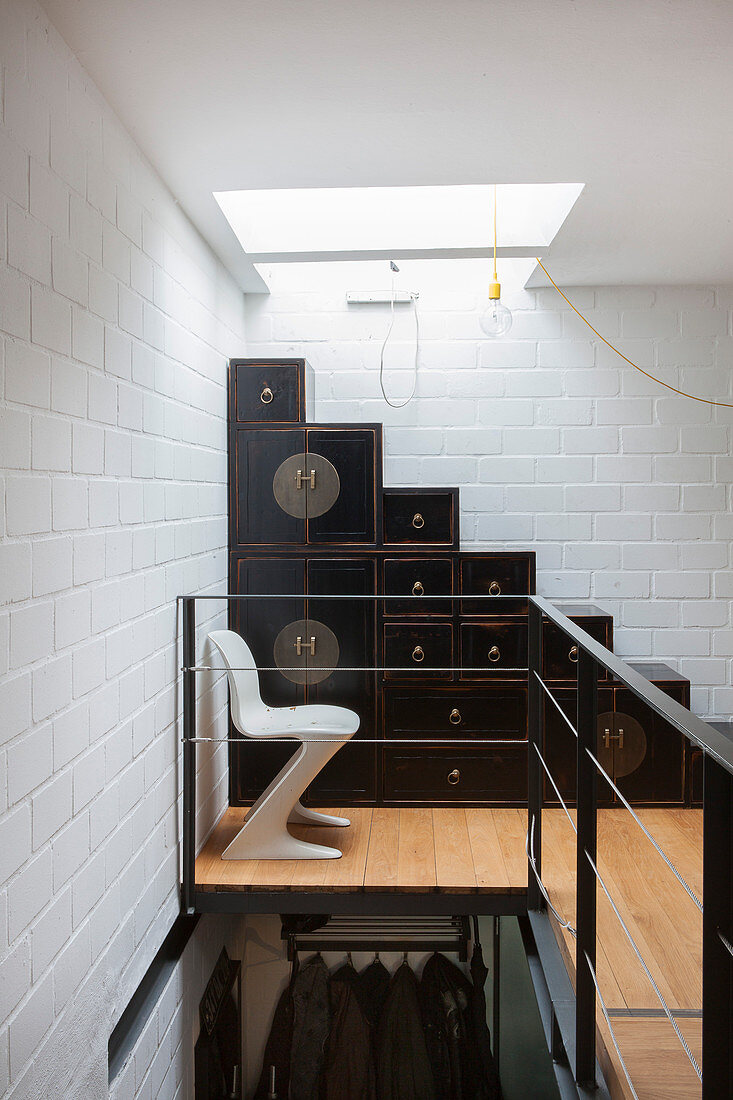 White designer chair in front of staircase made from Oriental cabinets