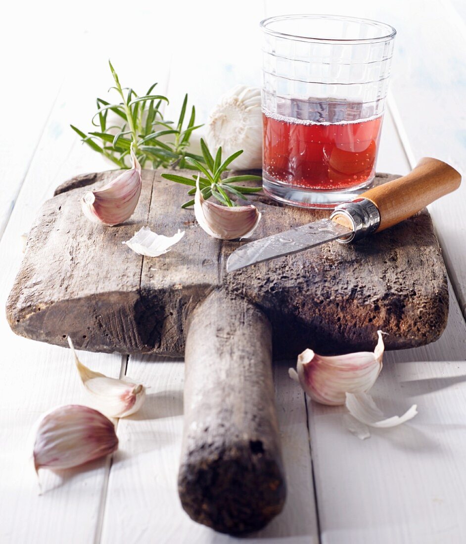 Cloves of garlic with red wine and a knife on an old wooden board