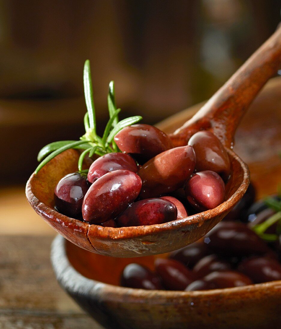 Kalamata olives with rosemary in a wooden ladle