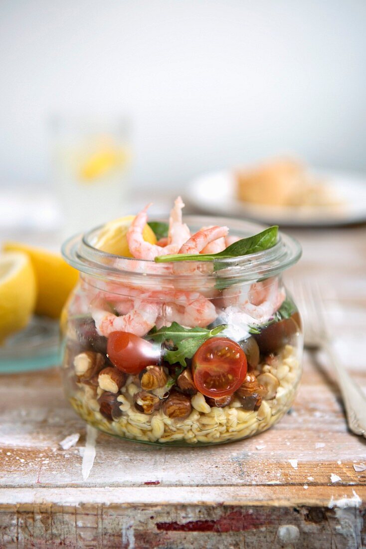 Lunch in a glass jar: shrimp, tomatoes, hazelnuts, rocket and wheat