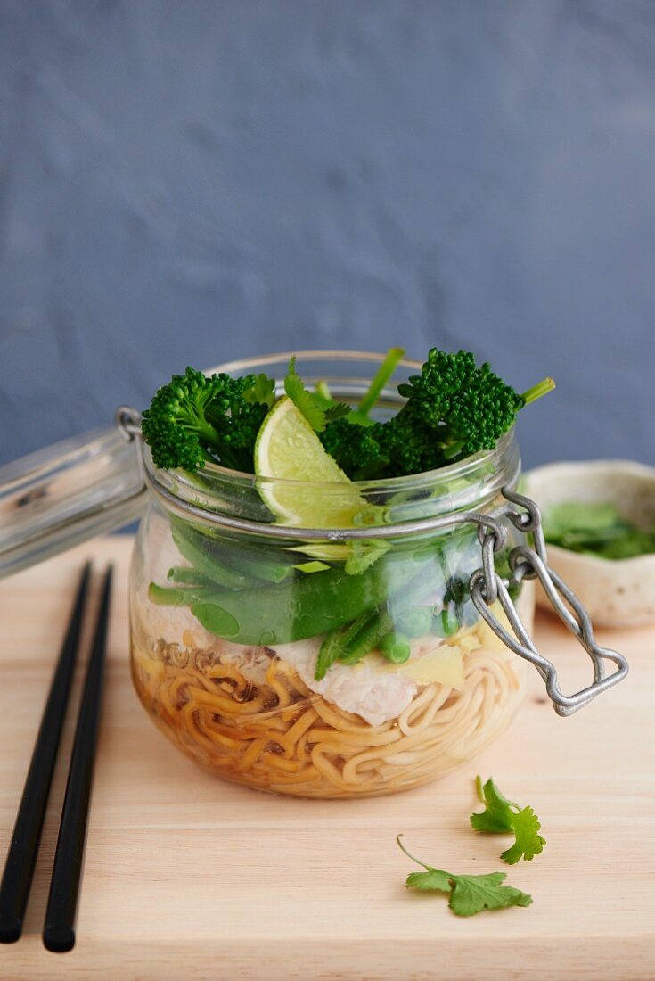 Noodles with chicken, sugar snaps and broccoli in a glass jar (Asia)