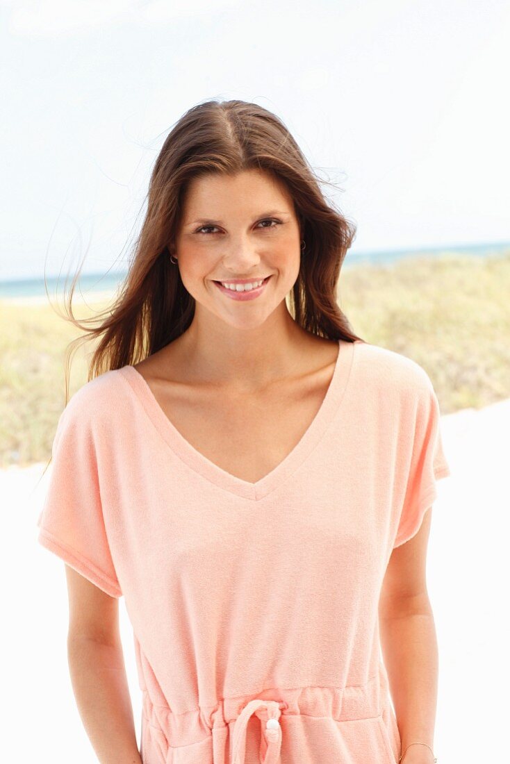 A brunette woman wearing a salmon-coloured jersey dress