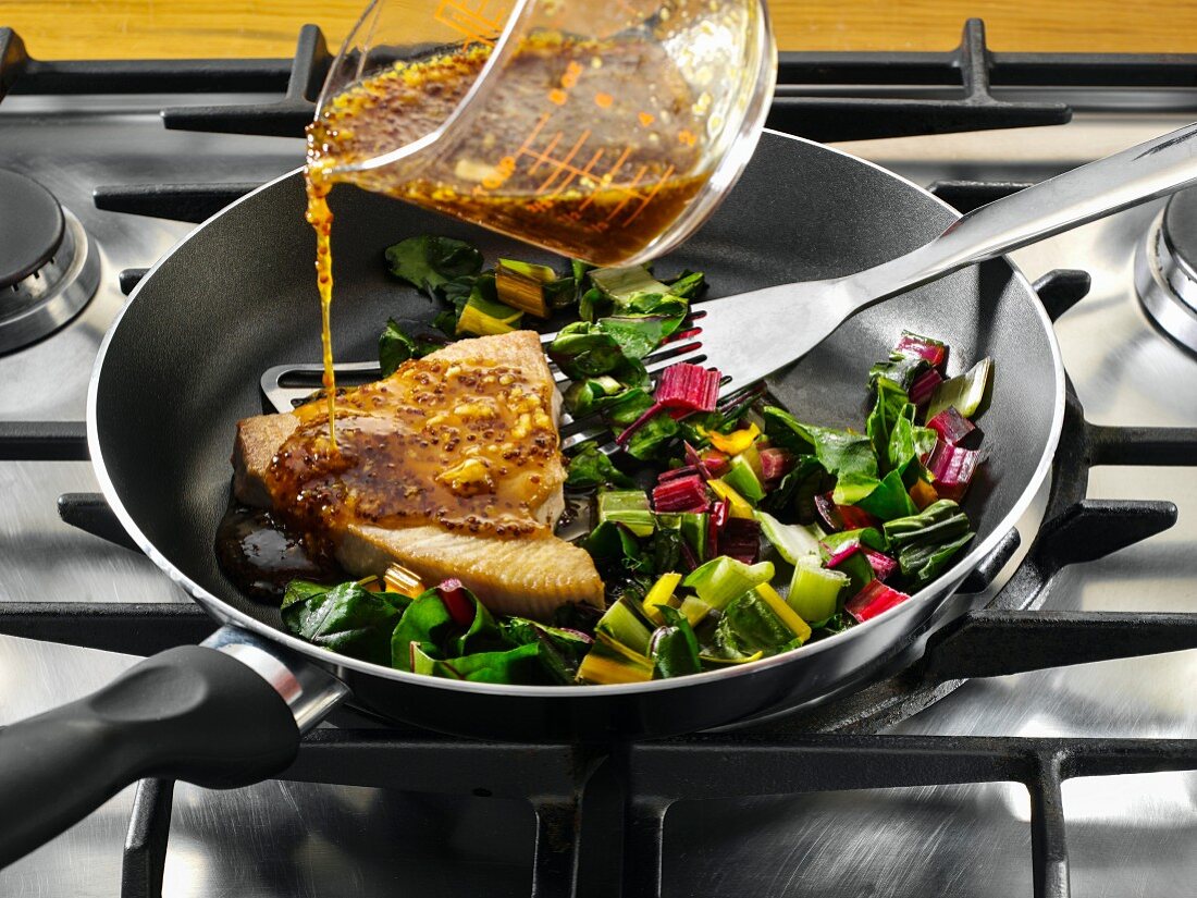 Thunfisch mit Mangoldgemüse in der Pfanne wird mit Tamarisauce begossen