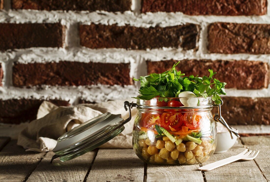 Salad with chickpeas, tomatoes and parsley in a glass jar