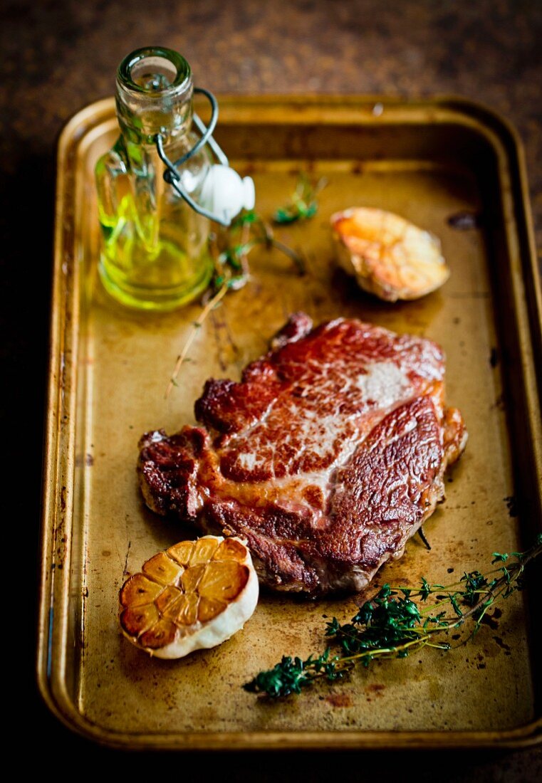A steak with garlic on a roasting tray