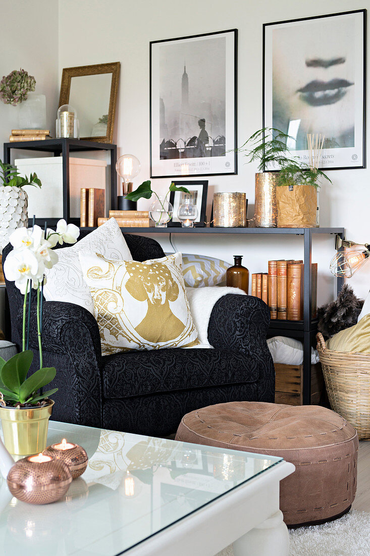 Armchair and pouffe in front of ornaments on open shelves