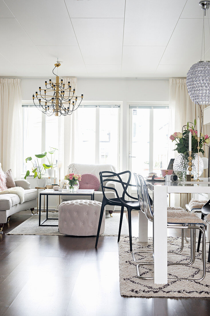 Dining table in open-plan living space with sofa set and coffee table in from of large windows in background