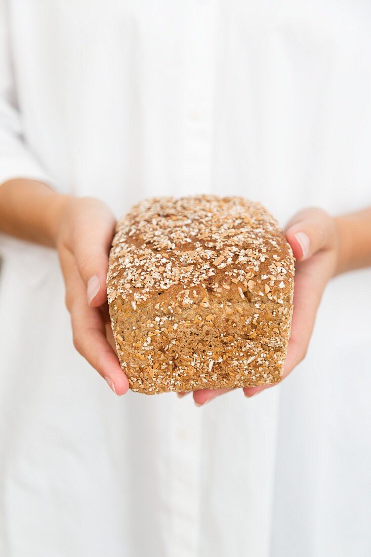 A woman holding a loaf of oat bread