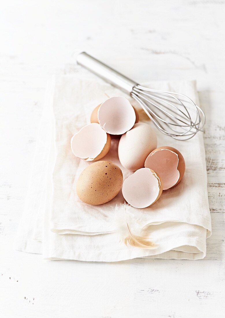 Organic eggs and a whisk on a kitchen towel