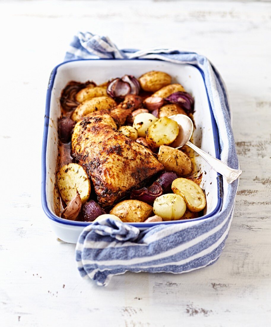 Oven-roasted chicken leg with young potatoes, onions and garlic