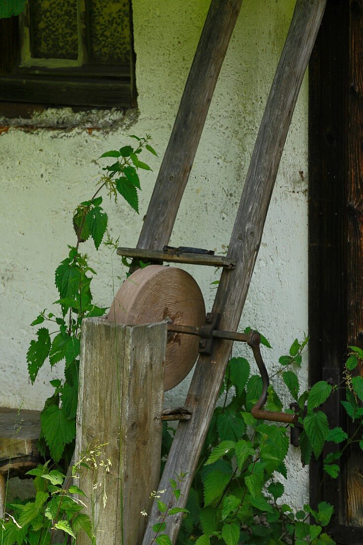 Old sharpening stone leaning against house façade in garden