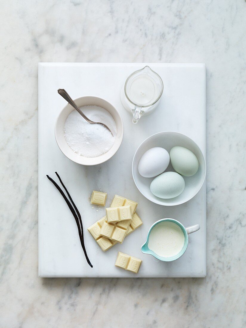 Various baking ingredients: sugar, milk, eggs, vanilla pods, flour and white chocolate