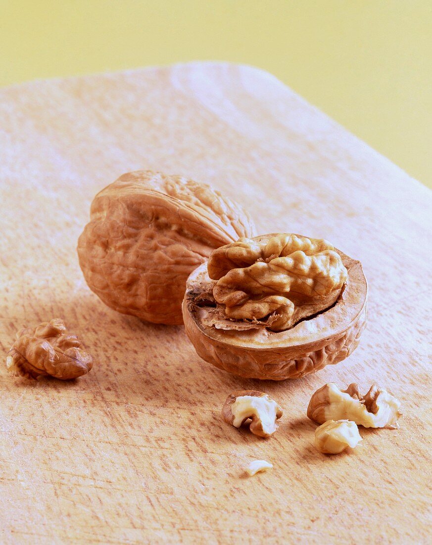 Two walnuts, whole and halved, on a wooden table