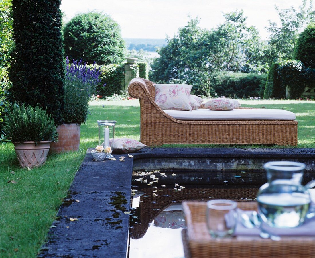 Chaiselongue aus Korb am Pool im klassischen Sommergarten