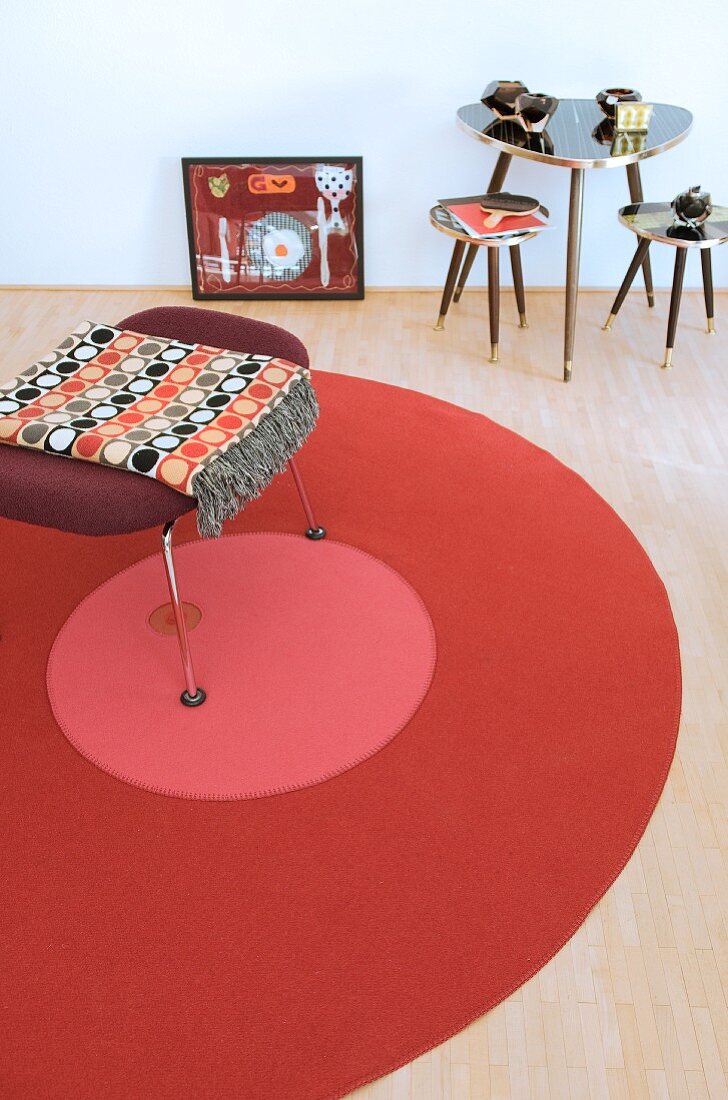 Stool on round rug next to three small retro tables
