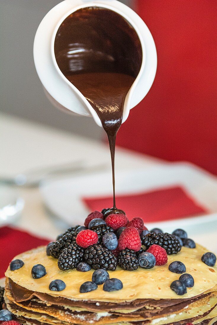 A pancake cake with berries and chocolate sauce