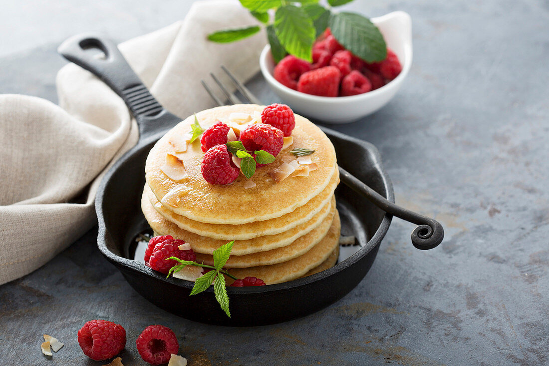 Stack of fluffy buttermilk pancakes with raspberry and coconut for breakfast