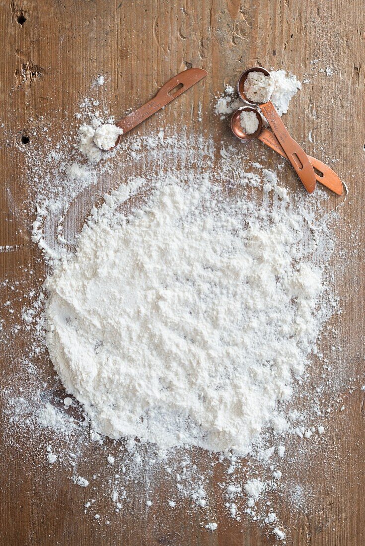 A flour-covered wooden board with flour with measuring spoons