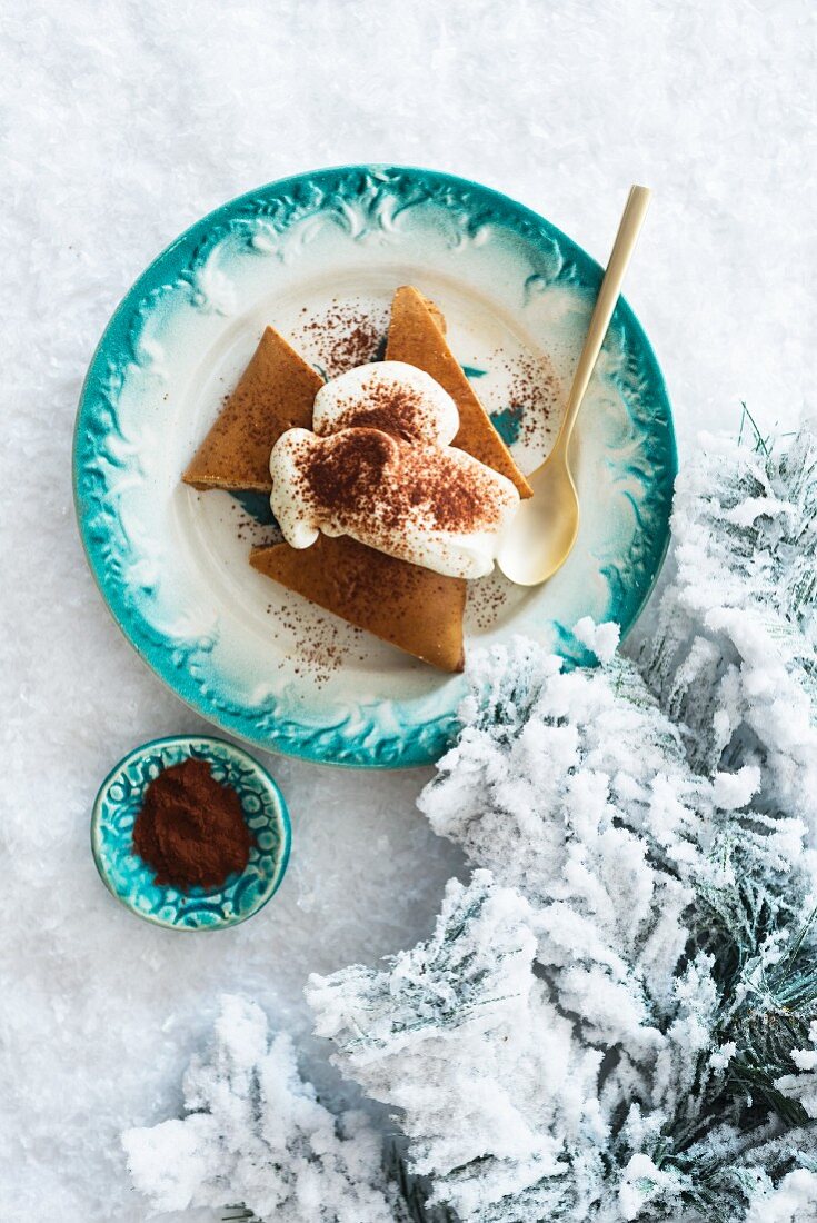 Festive gingerbread cake with whipped cream on a plate in the snow