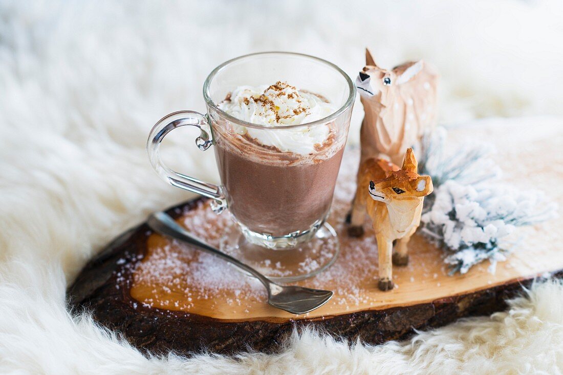 Hot chocolate in a glass cup with wood-carved deer figures