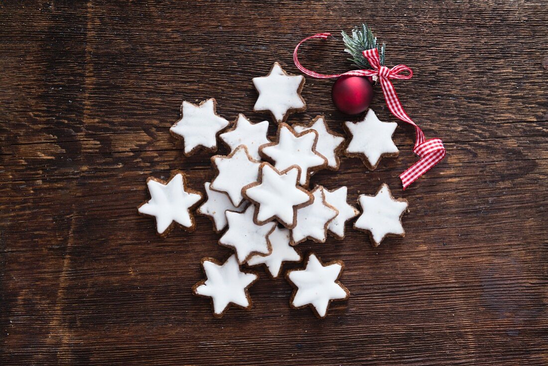 Cinnamon stars and a red bauble on a wooden background