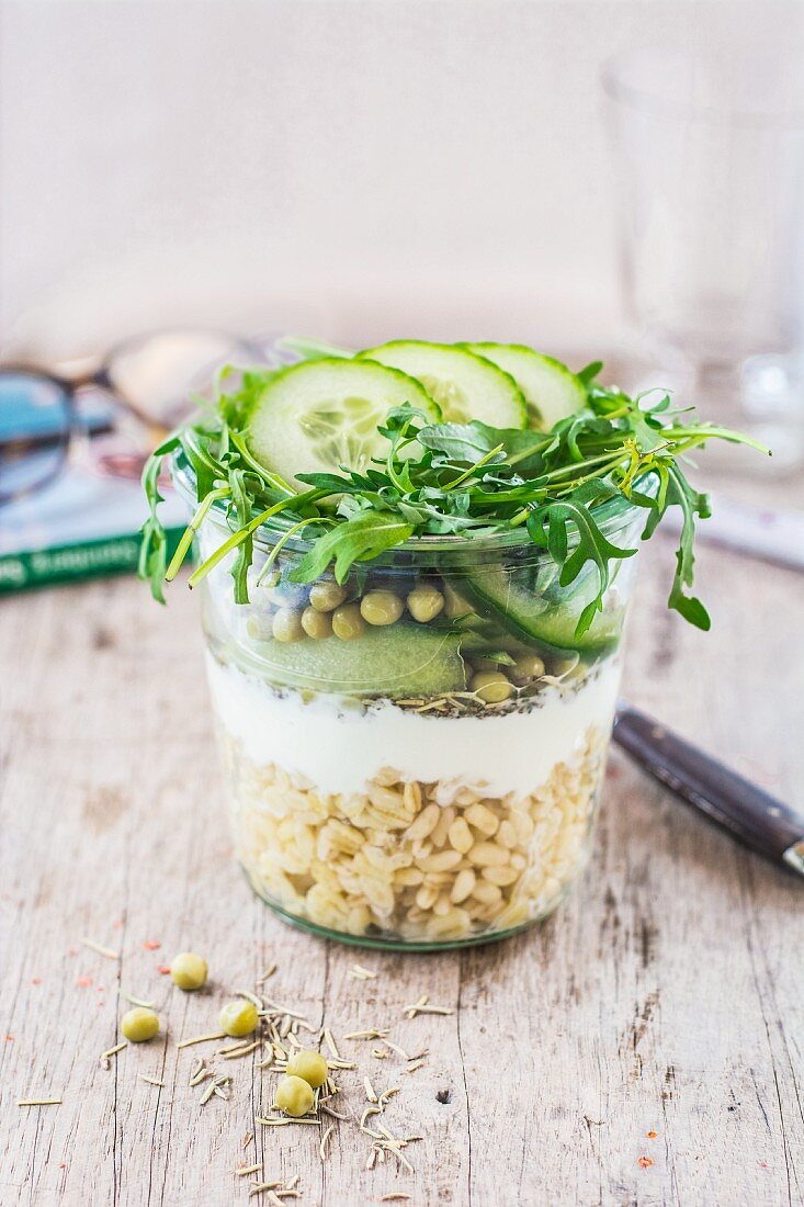Geschichteter Erbsen-Gurken-Salat mit Weizen, Joghurt und Rucola im Glas