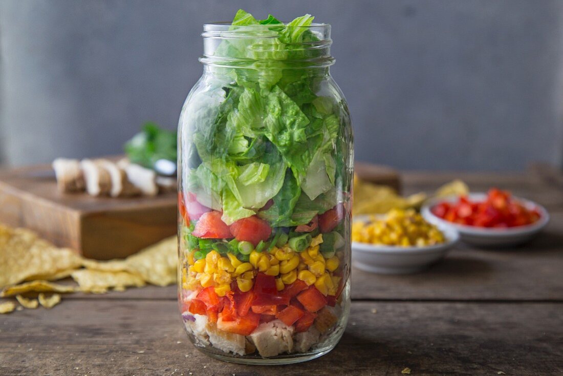 Layered salad with chicken breast, red pepper, sweetcorn, romaine lettuce, tomato and tortilla chips