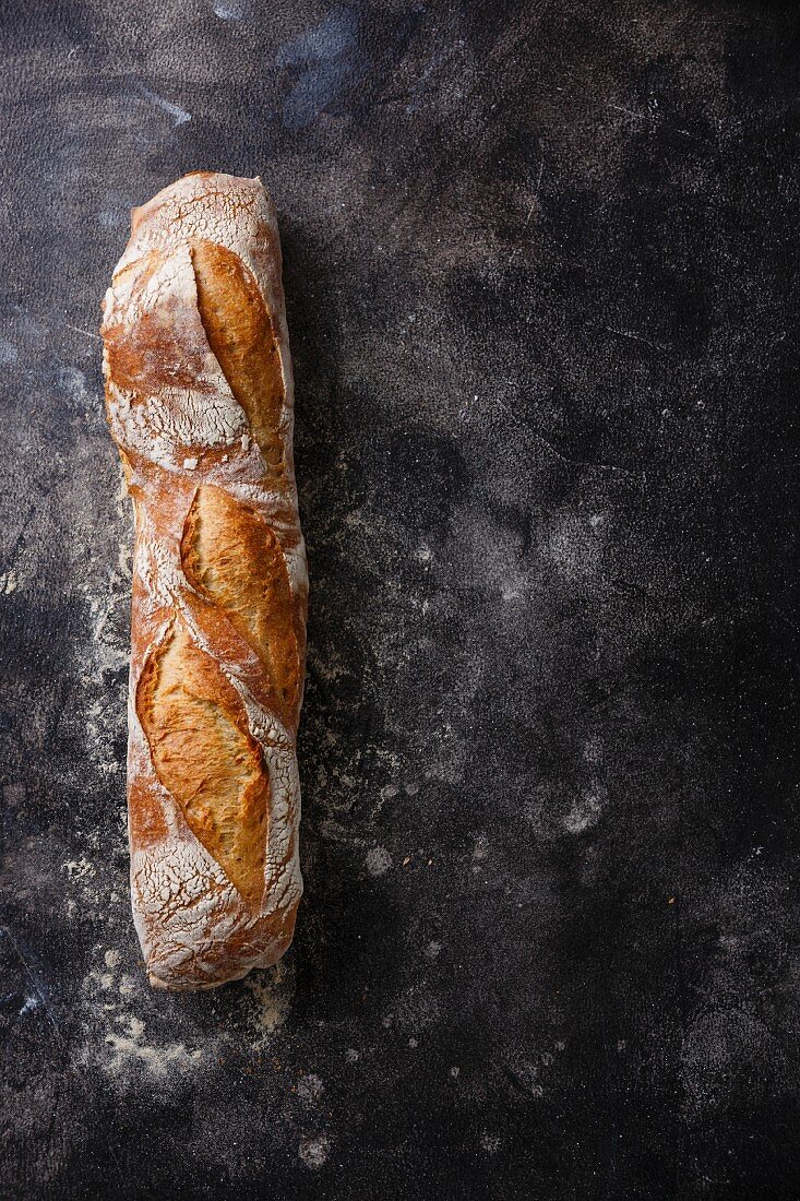 Ein frisches Baguette auf dunklem Untergrund (Aufsicht)