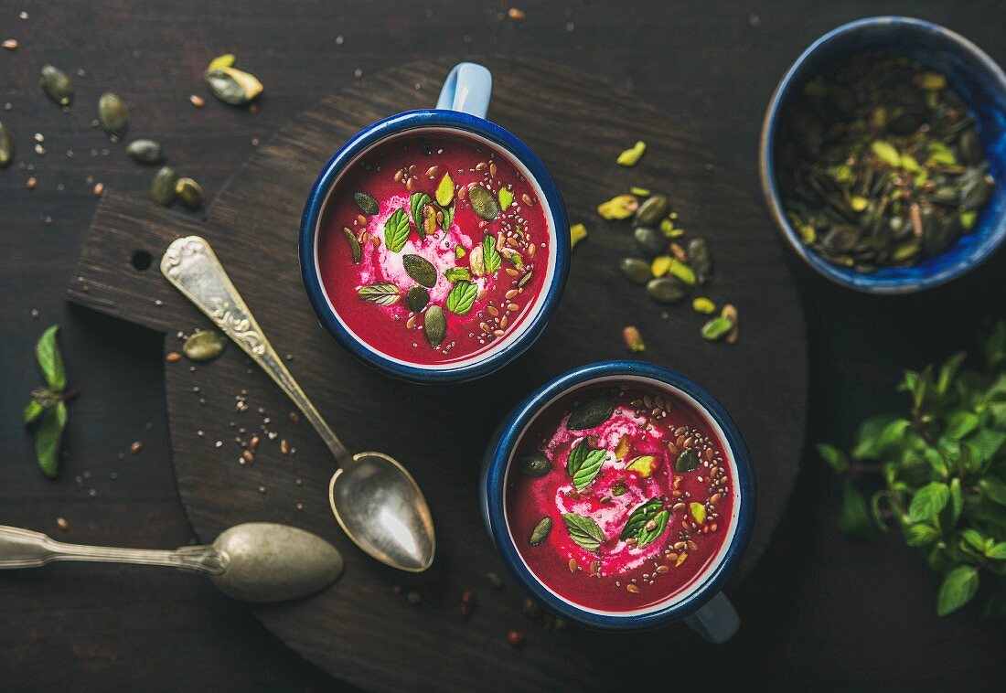 Spring detox beetroot soup with mint, pistachio, chia, flax and pumpkin seeds in blue enamel mugs