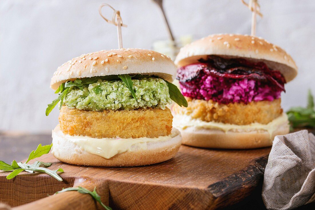 Two vegetarian hamburgers with onion and cheese cutlets, avocado salad, arugula, fried beetroot and yogurt sauce