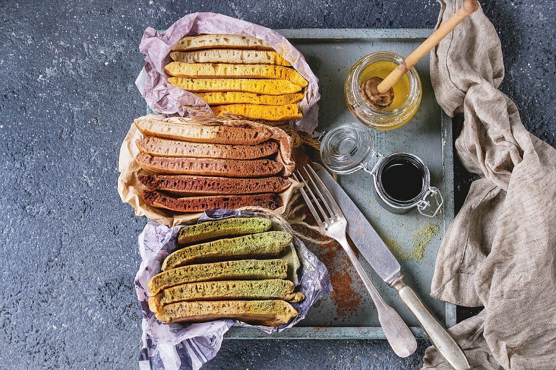 Variety of sliced american ombre chocolate, green tea matcha and turmeric pancakes with honey sauces