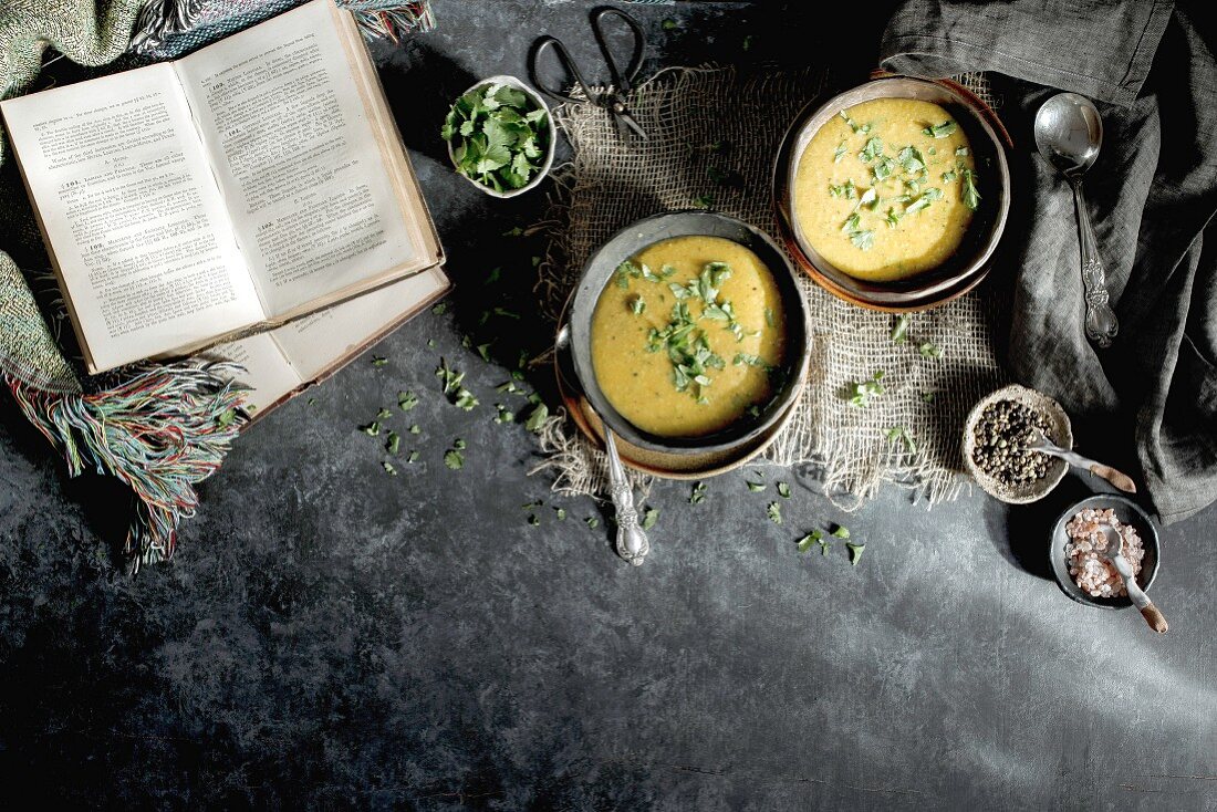 Linsensuppe in Schälchen, daneben Gewürze und Bücher (Indien)