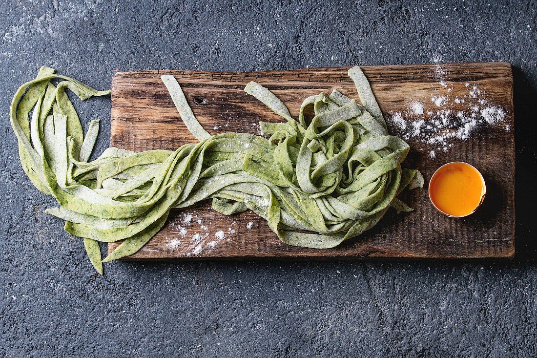 Fresh raw uncooked homemade green spinach pasta tagliatelle with egg yolk and flour