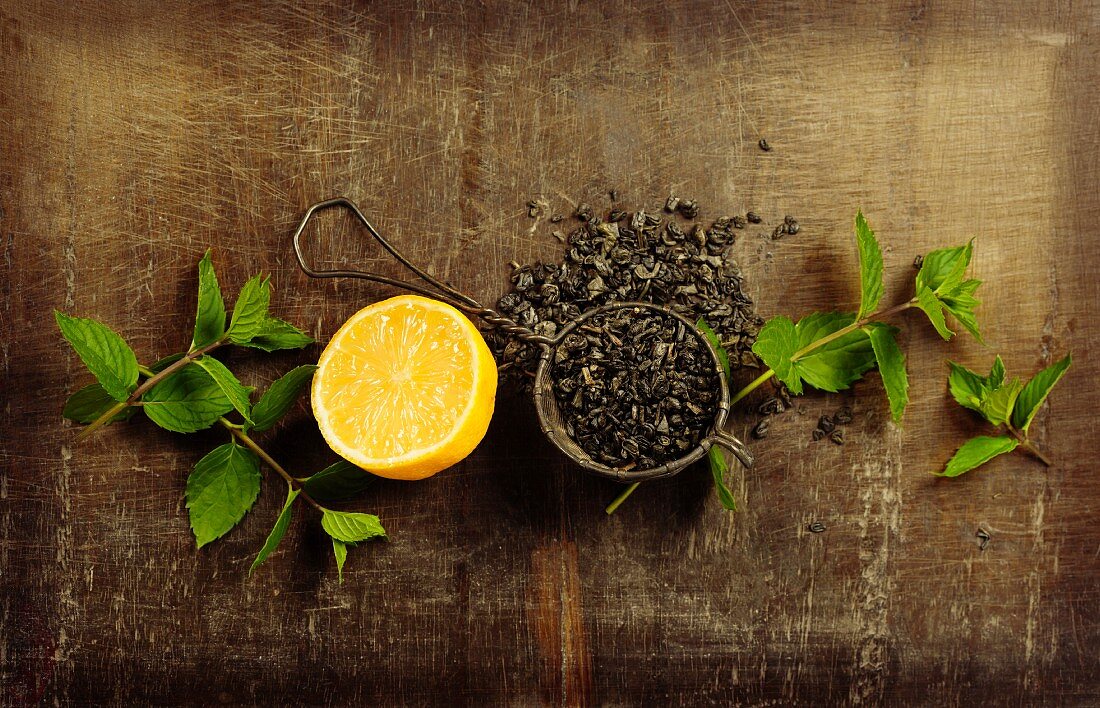 Dry tea with mint and lemon on wooden table, top view